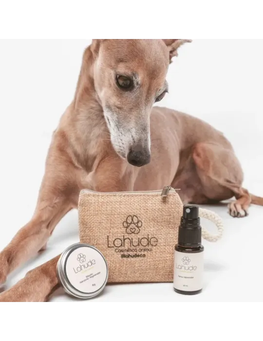 Galgo junto al neceser de Lahude, bálsamo hidratante regenerador y spray reparador en tamaño mini.