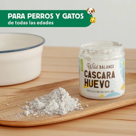 Bote abierto de Wild Balance Cáscara de Huevo con su contenido en polvo sobre tabla de madera, suplemento para perros y gatos.