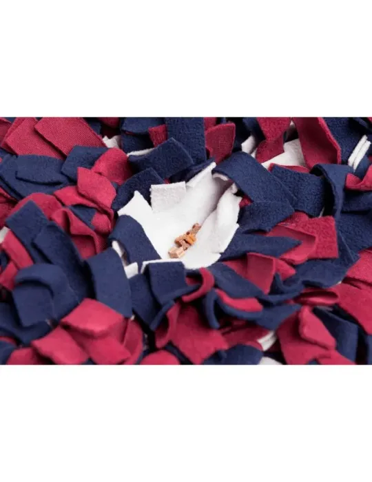 Detalle de alfombra olfativa para perros con snacks ocultos entre tiras de tela rojas, azules y blancas.