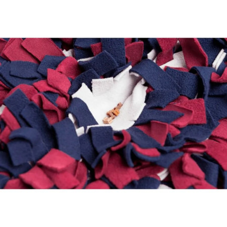 Detalle de alfombra olfativa para perros con snacks ocultos entre tiras de tela rojas, azules y blancas.