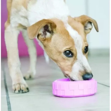 Cachorro jugando con el juguete KONG Puppy Tyres rosa, masticando el caucho para aliviar las encías.