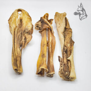 Tres piezas de caravaca de cabra deshidratada con diferentes formas y texturas, ideales como snack duradero para perros.