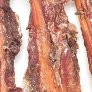 Detalle extremo de los tendones de ciervo con carne, mostrando las fibras y el color de la carne deshidratada.
